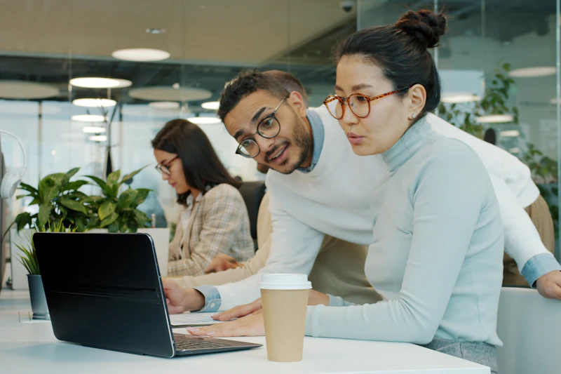 Zwei Kolleginnen und Kollegen arbeiten gemeinsam an einem Laptop